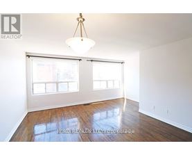 A room with a wooden floor and a large window with blinds.