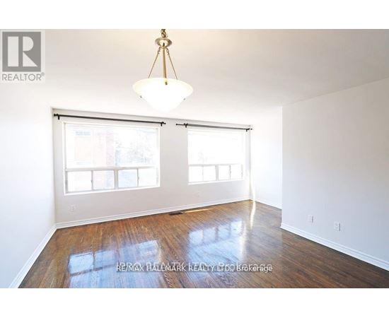 A room with a wooden floor and a large window with blinds.