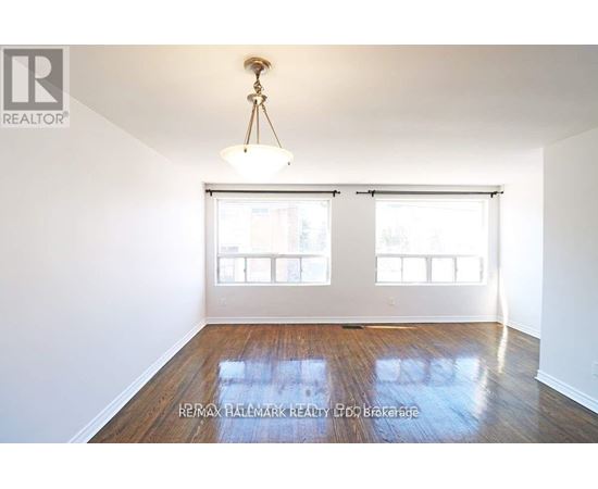A room with a wooden floor and a chandelier hanging from the ceiling.