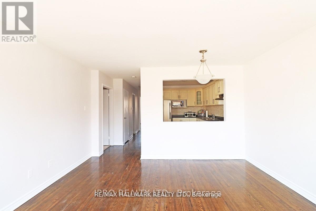 A realtor photo of an empty room with a picture of a kitchen in the background.