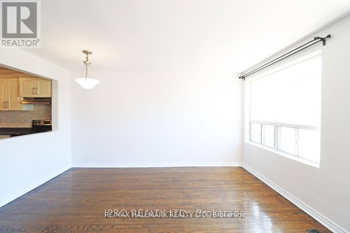 A room with a wooden floor and a window with blinds.