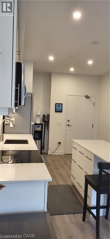 A modern kitchen with white cabinets and a black chair.