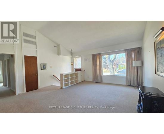 A spacious living room with a carpeted floor and a large window with curtains.