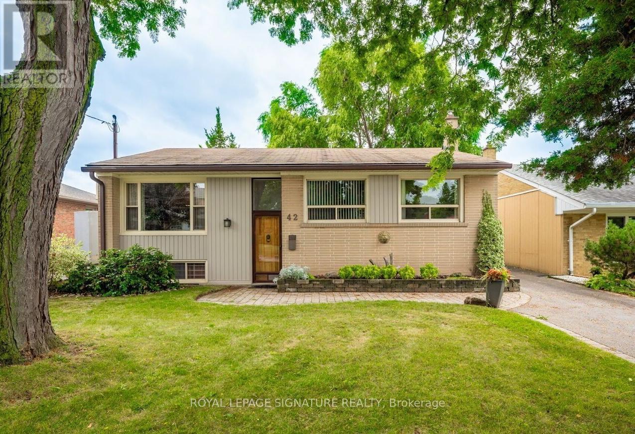A house with a brown door and windows is surrounded by greenery.