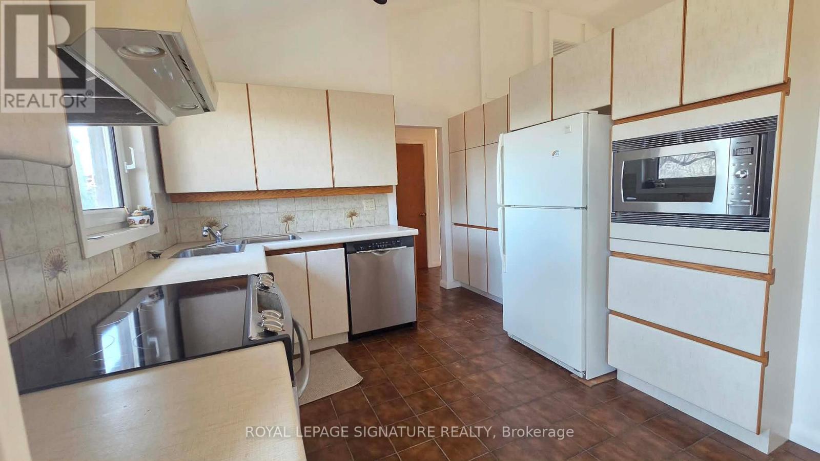 A kitchen with white cabinets and a white fridge.