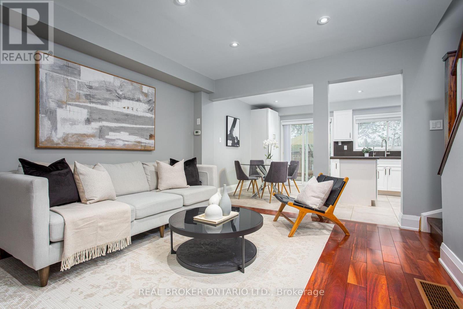 A living room with a grey couch, a coffee table, and a painting on the wall.