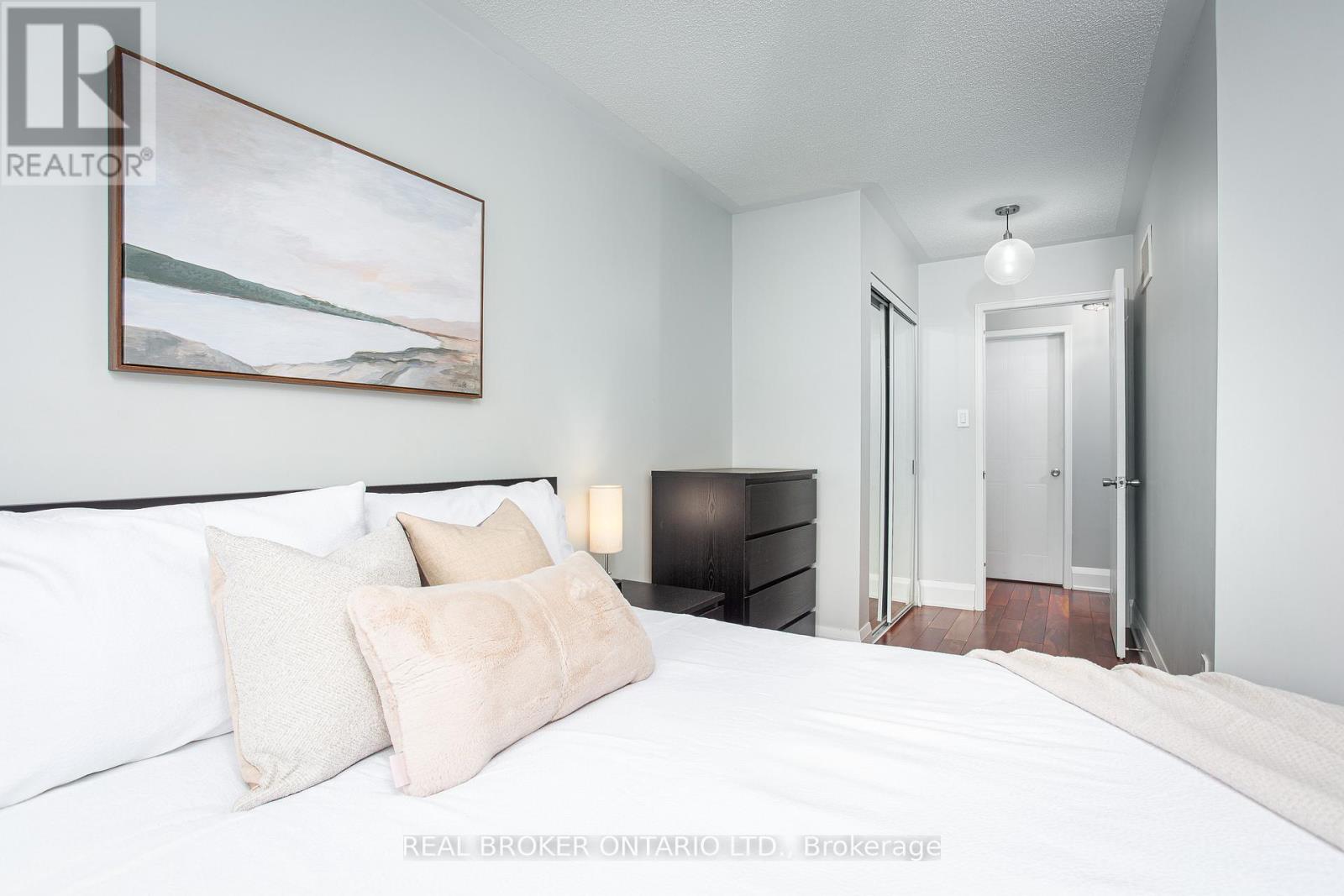 A bedroom with a large bed and a painting on the wall.