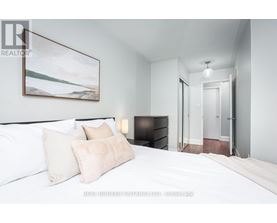 A bedroom with a large bed and a painting on the wall.