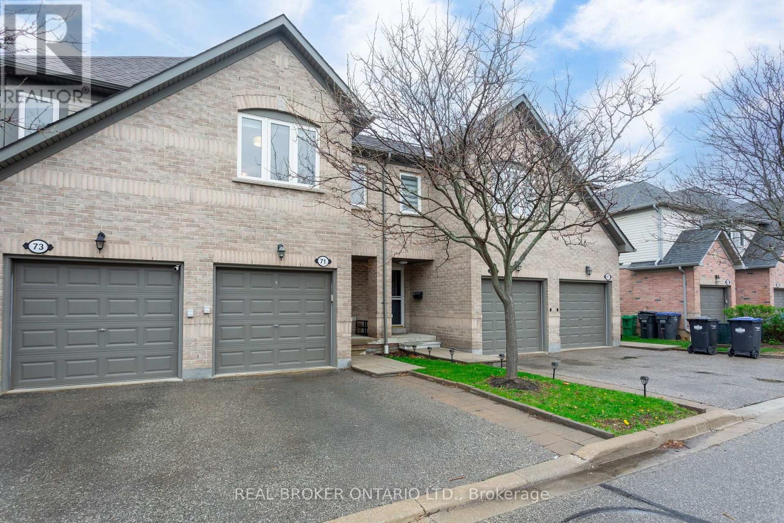 A house with a grey roof and a tree in front of it.