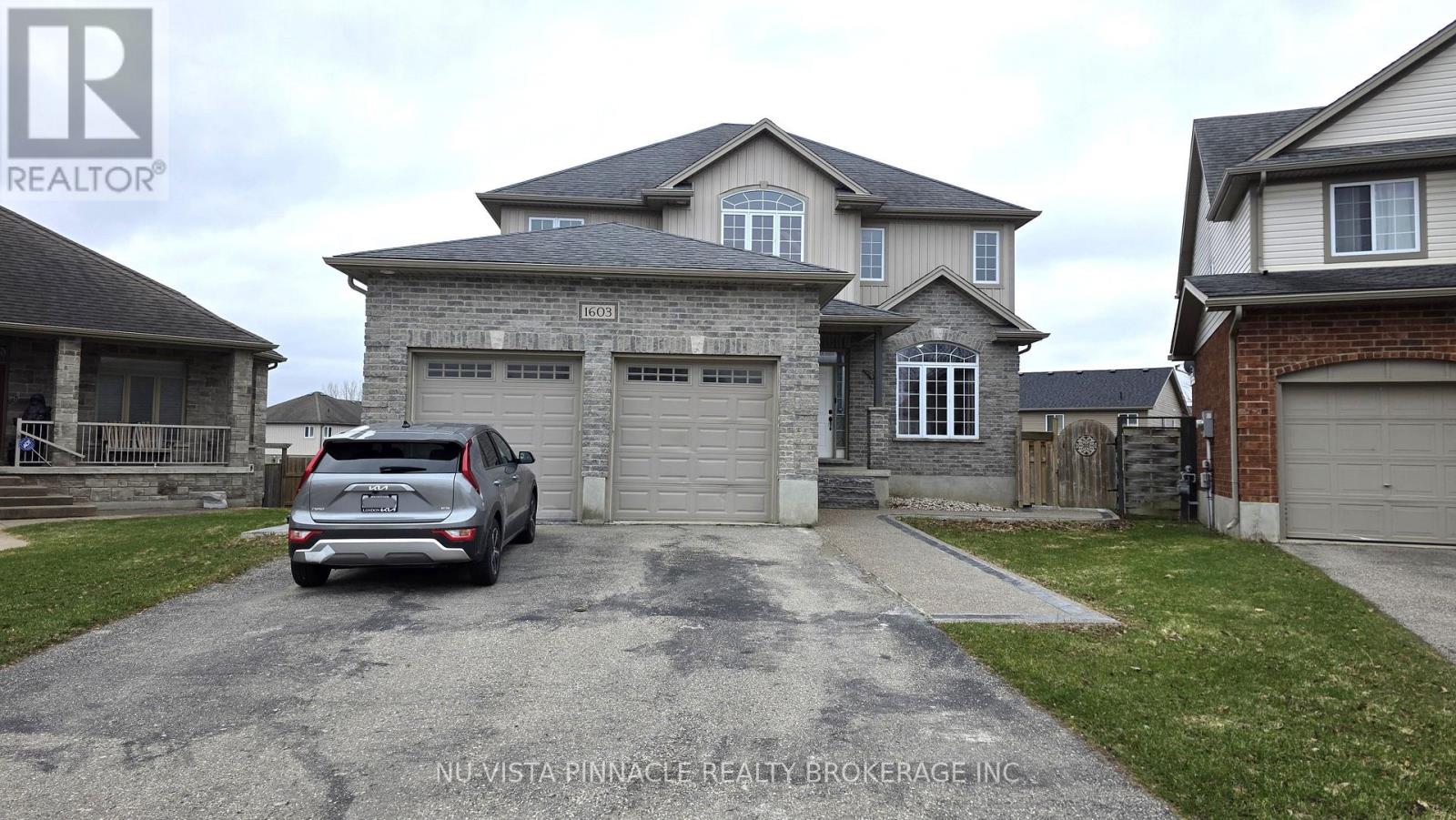 A grey house with a grey car in front of it.