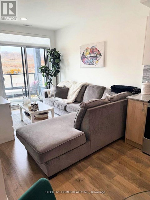 A living room with a grey couch and a painting on the wall.