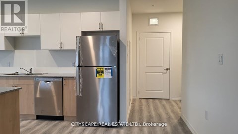 A kitchen with a stainless steel refrigerator and a door on the right.