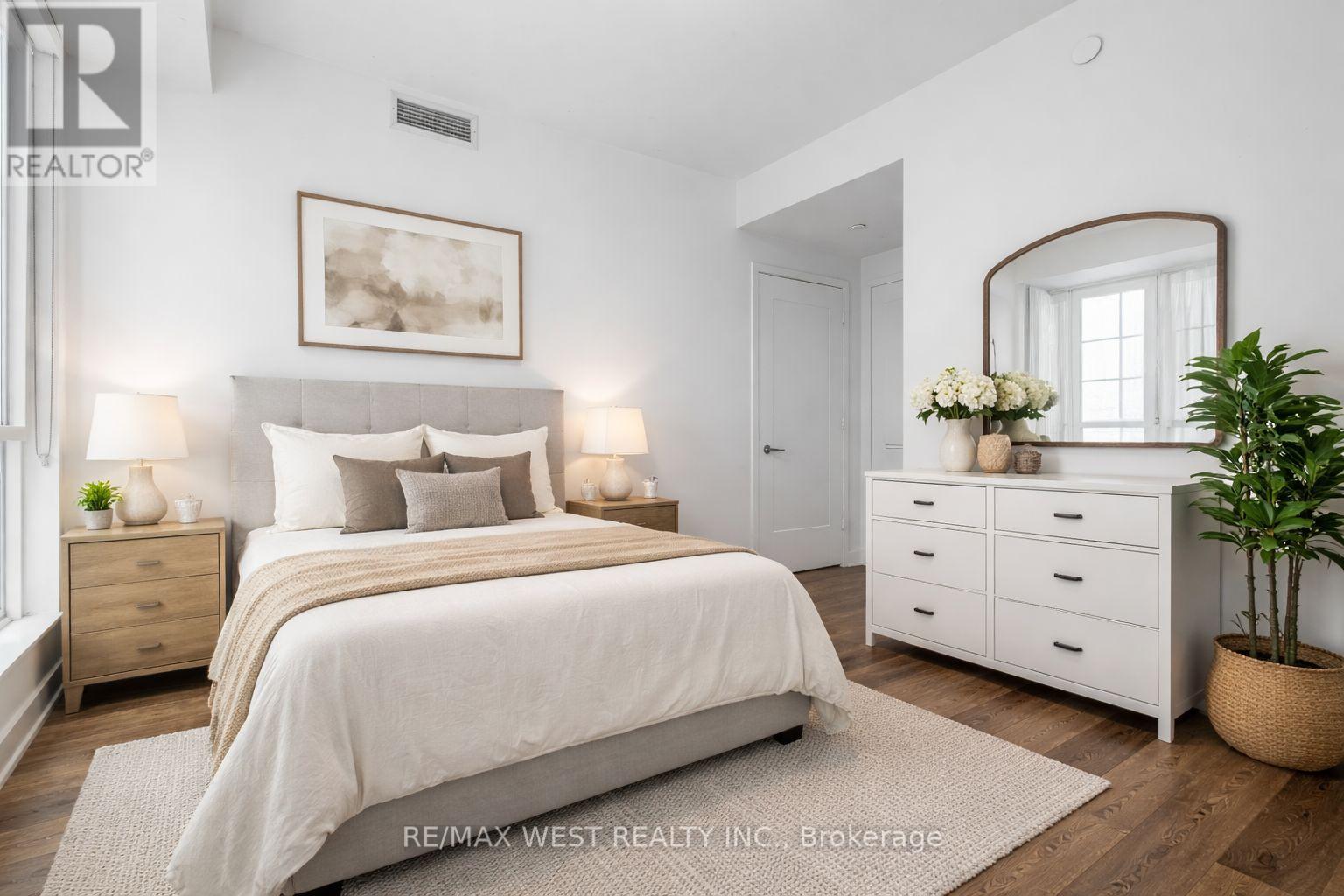 A bedroom with a large bed, a dresser, and a mirror.