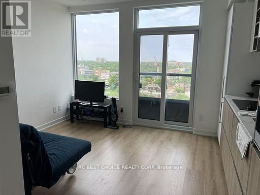 A living room with a television set on a stand and a window overlooking a cityscape.
