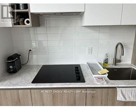 A kitchen counter with a black cutting board, a white keyboard, and a bottle of dish soap.