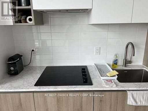 A kitchen counter with a black cutting board, a white keyboard, and a bottle of dish soap.