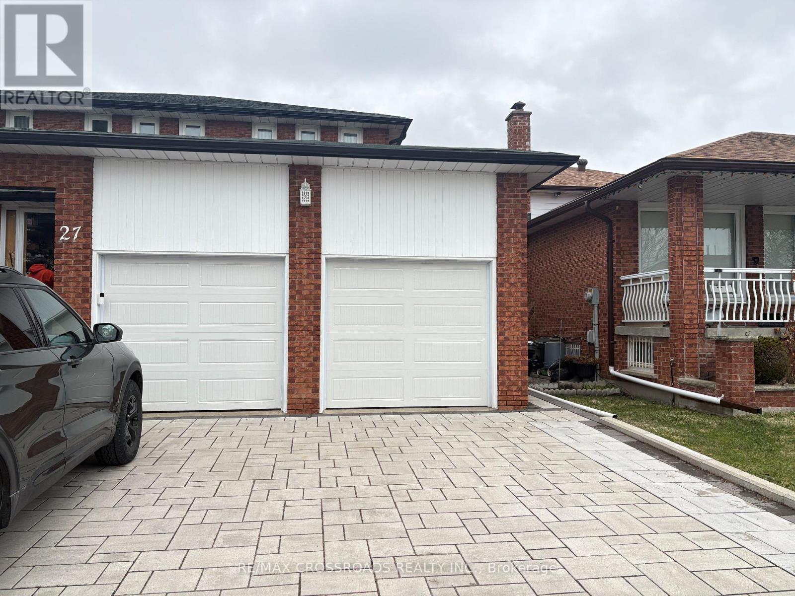 A black car is parked in front of a white garage door.