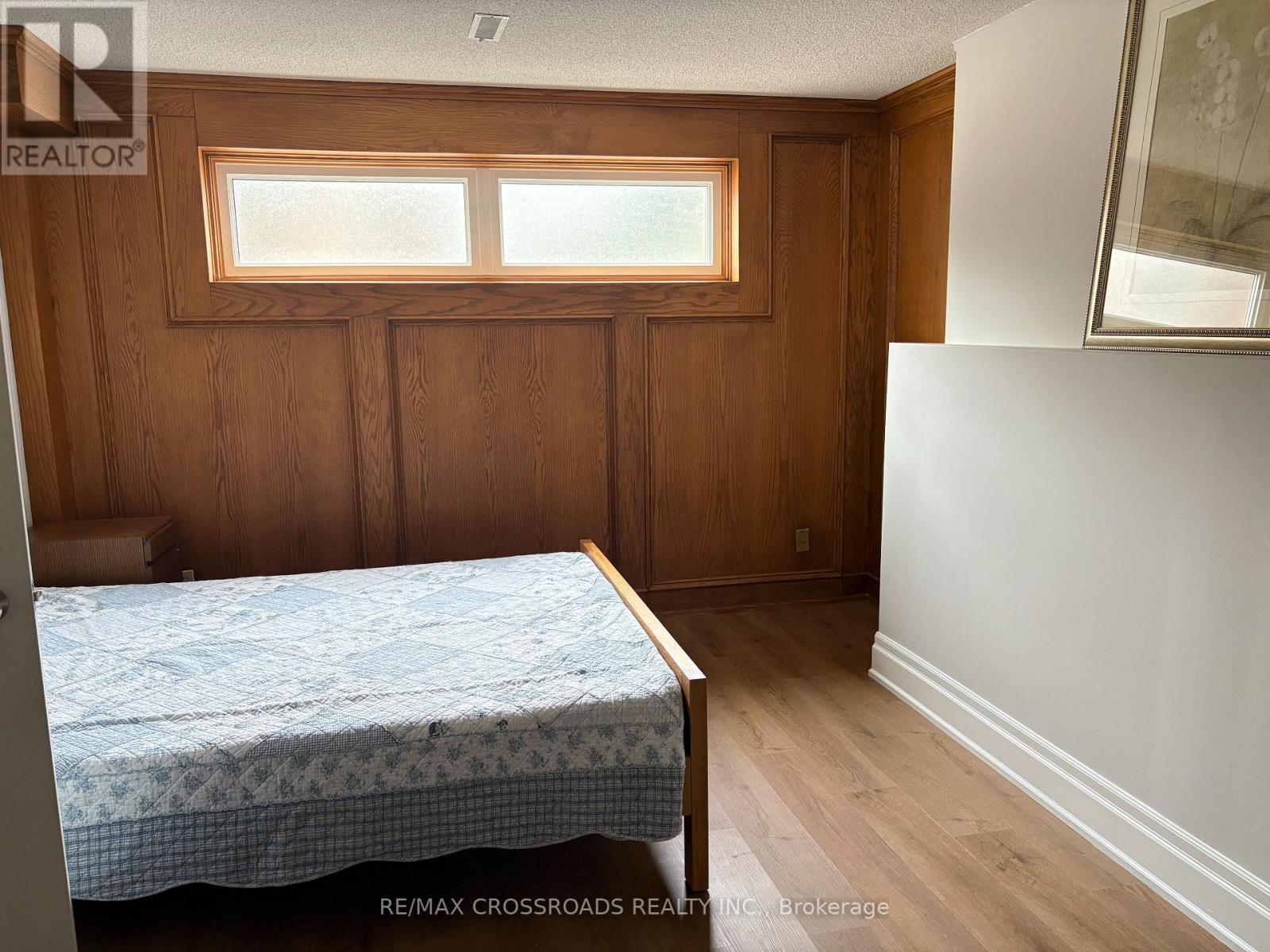 A bedroom with a bed, wooden walls, and a window.