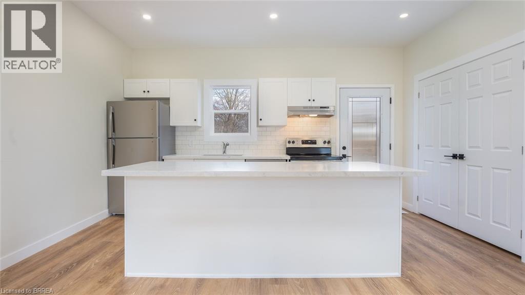 A white kitchen with a wooden floor and white cabinets.
