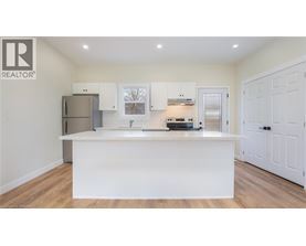 A white kitchen with a wooden floor and white cabinets.
