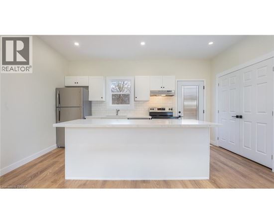 A white kitchen with a wooden floor and white cabinets.