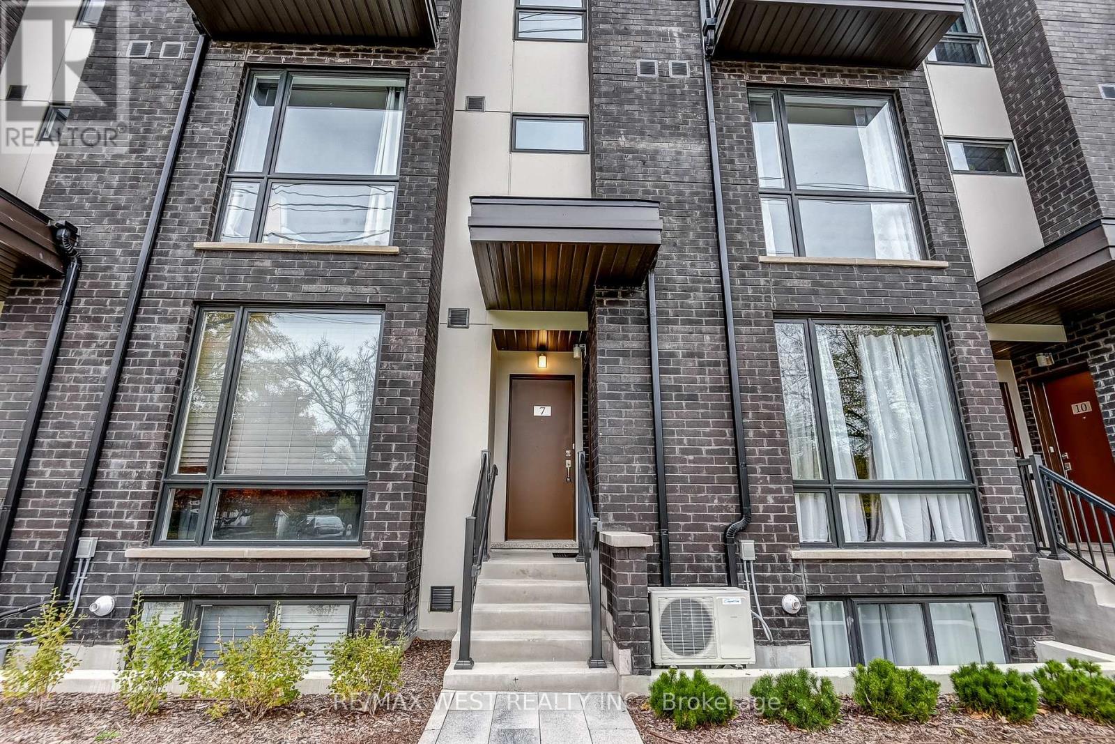 A modern apartment building with a brown door and windows.