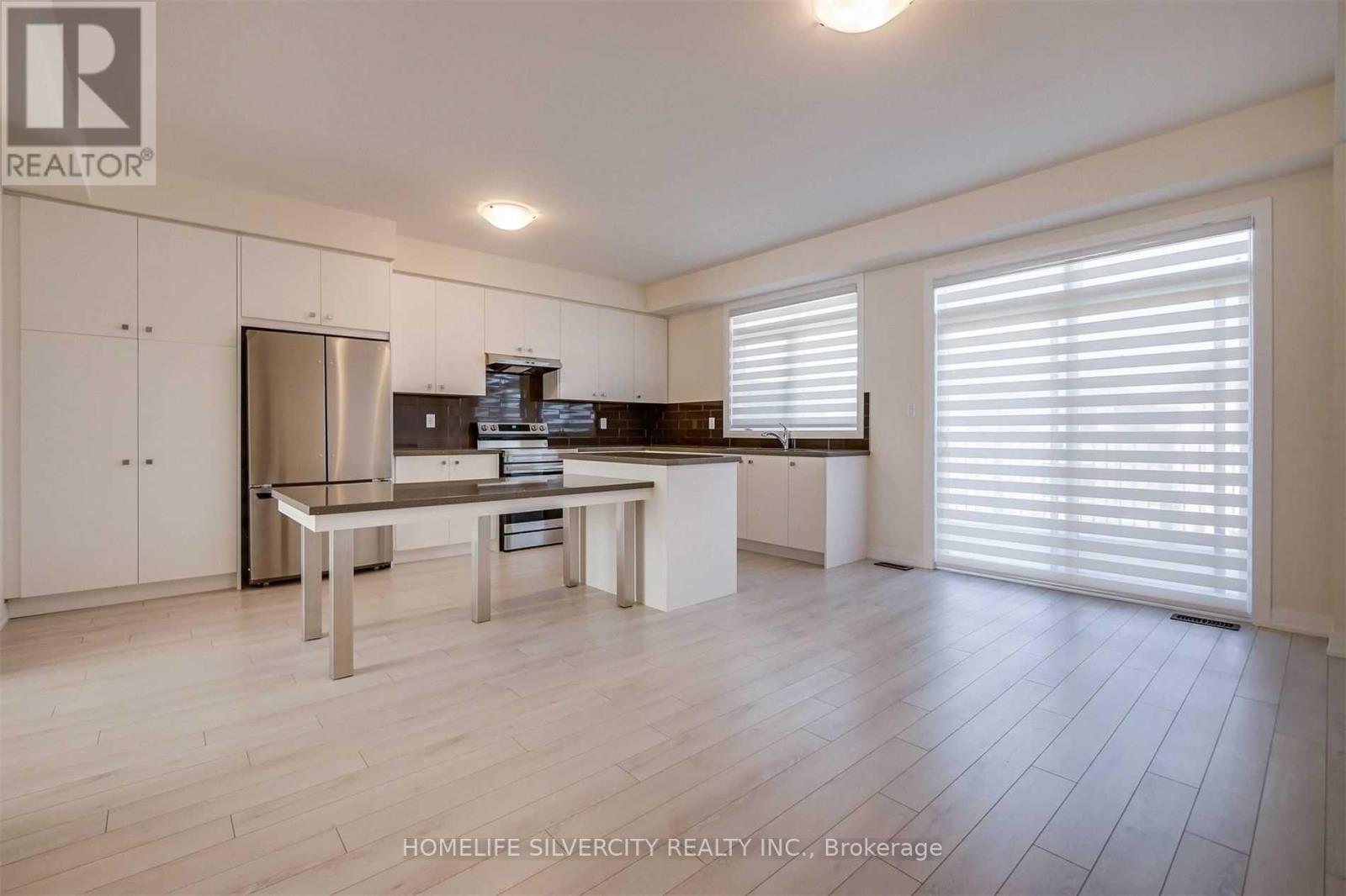 A modern kitchen with white cabinets and a stainless steel refrigerator.
