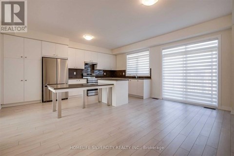 A modern kitchen with white cabinets and a stainless steel refrigerator.