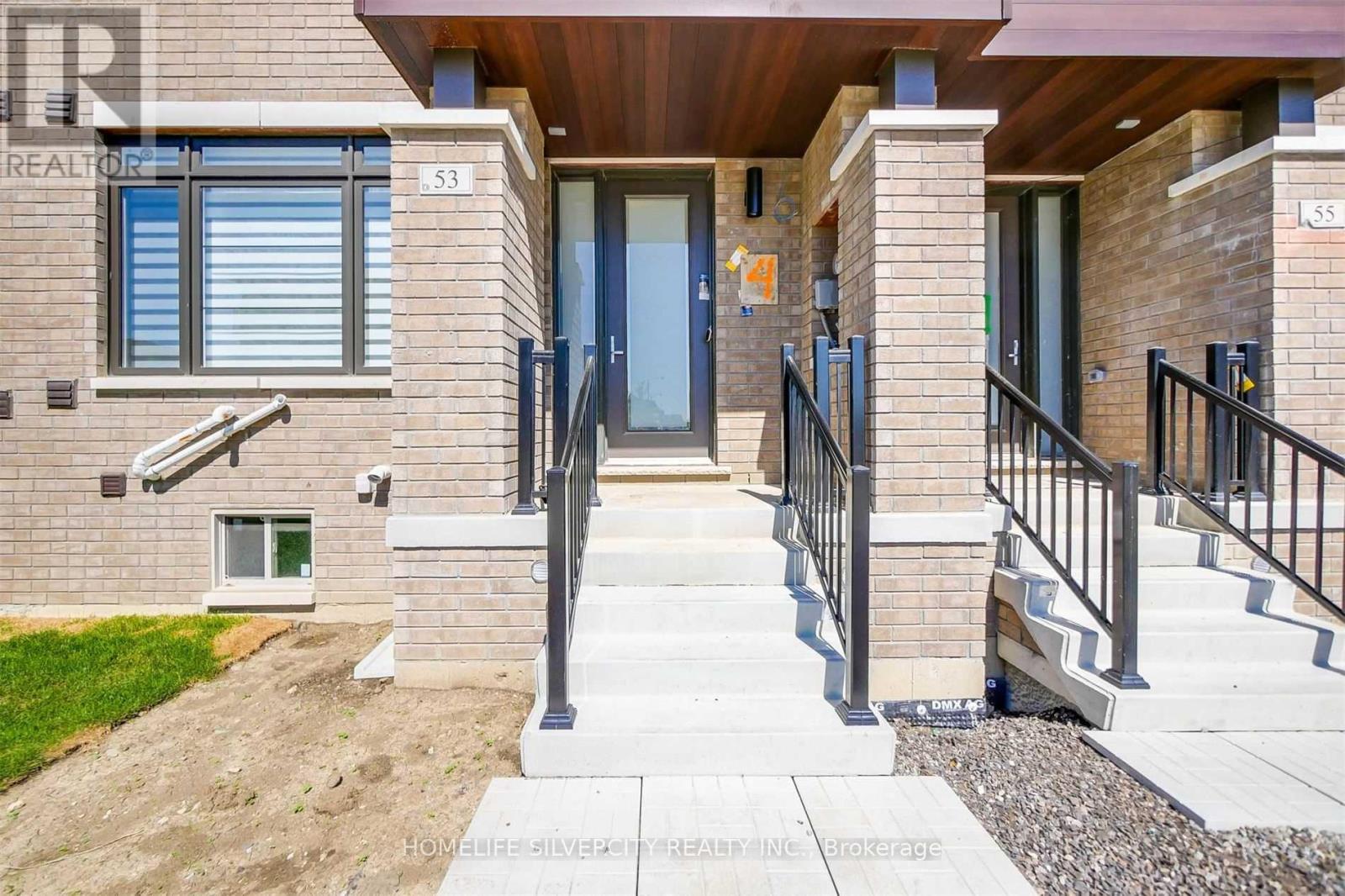A modern house with a front porch and a black railing.