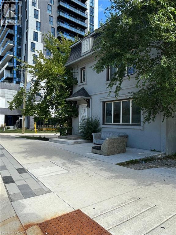 A white house with a brown door and windows is surrounded by a concrete walkway.