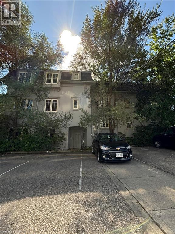 A black car is parked in front of a house with a tree on the left.