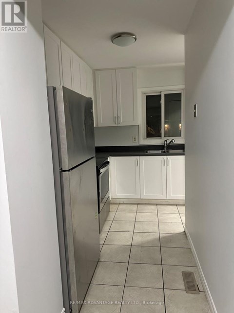 A kitchen with white cabinets and a stainless steel refrigerator.