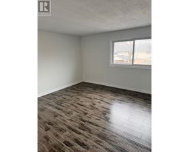 A room with a window and a wooden floor.