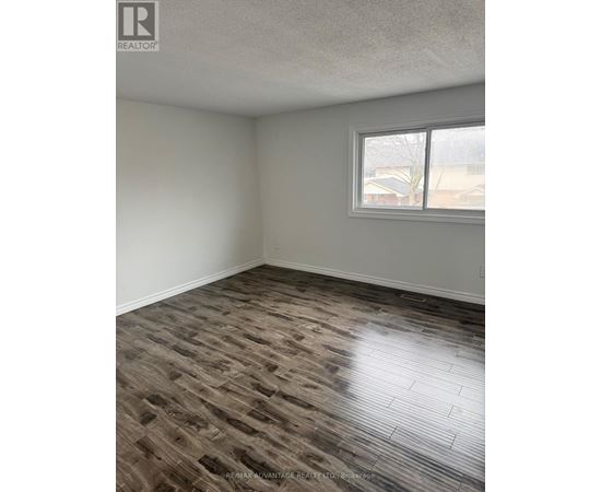 A room with a window and a wooden floor.