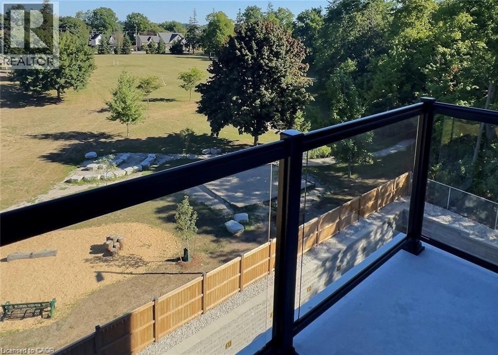 A balcony overlooks a sandy area with a tree and a playground.