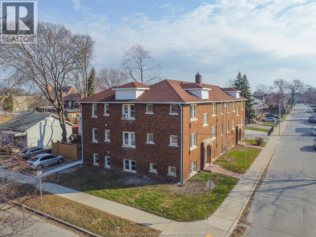 A brick apartment building with a white roof and a car parked in front.