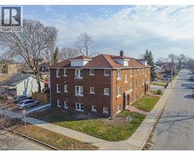 A brick apartment building with a white roof and a car parked in front.