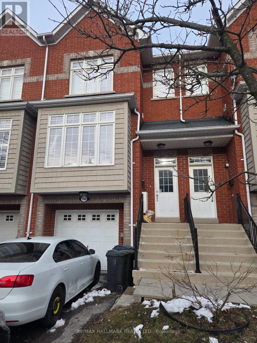 A white car is parked in front of a brown and beige house.