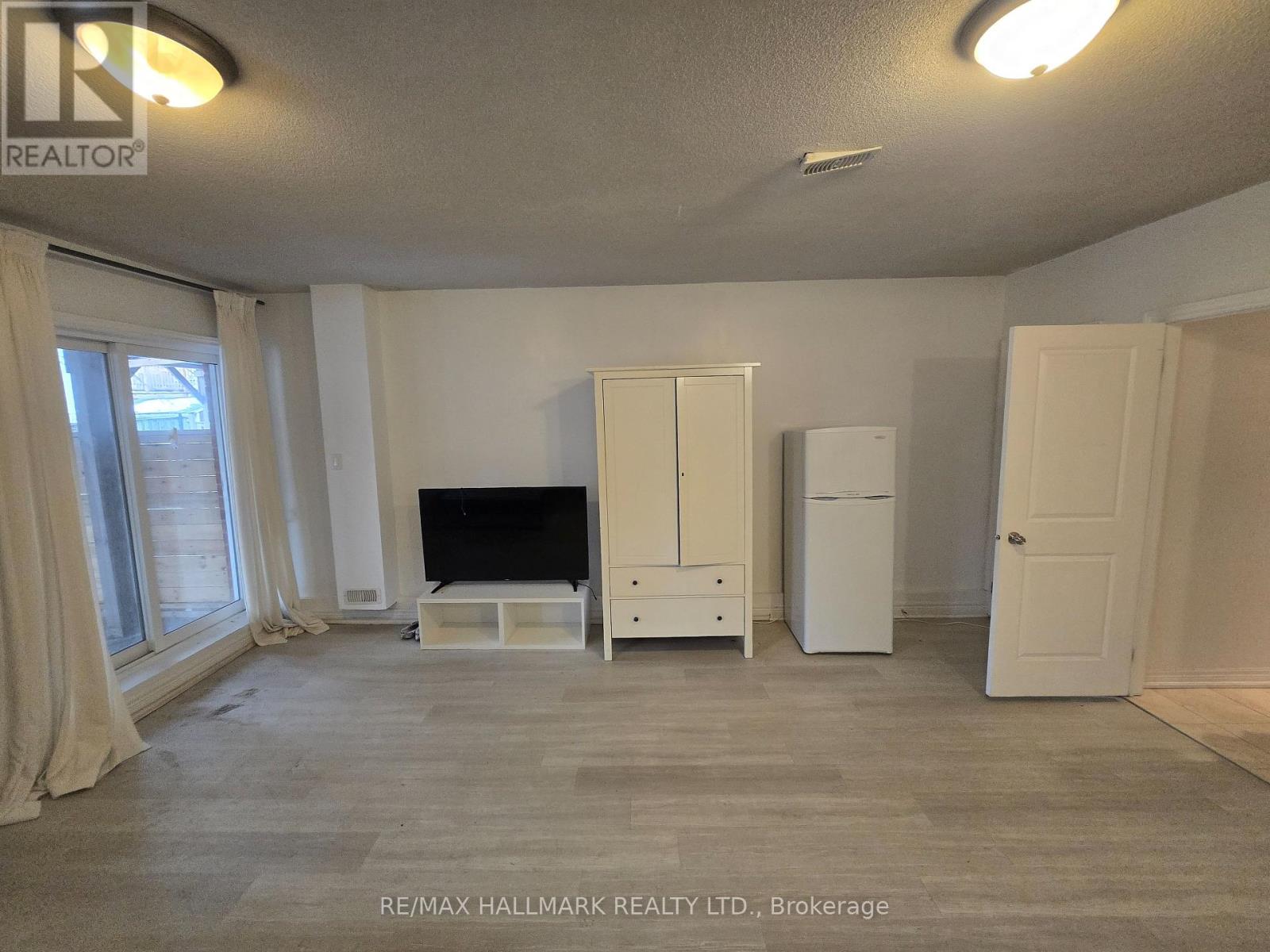 A living room with a television, a white cabinet, and a white fridge.