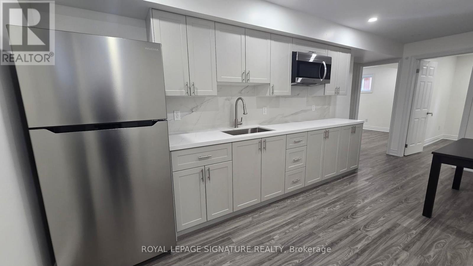A modern kitchen with a stainless steel refrigerator and white cabinets.