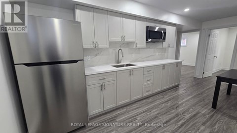 A modern kitchen with a stainless steel refrigerator and white cabinets.