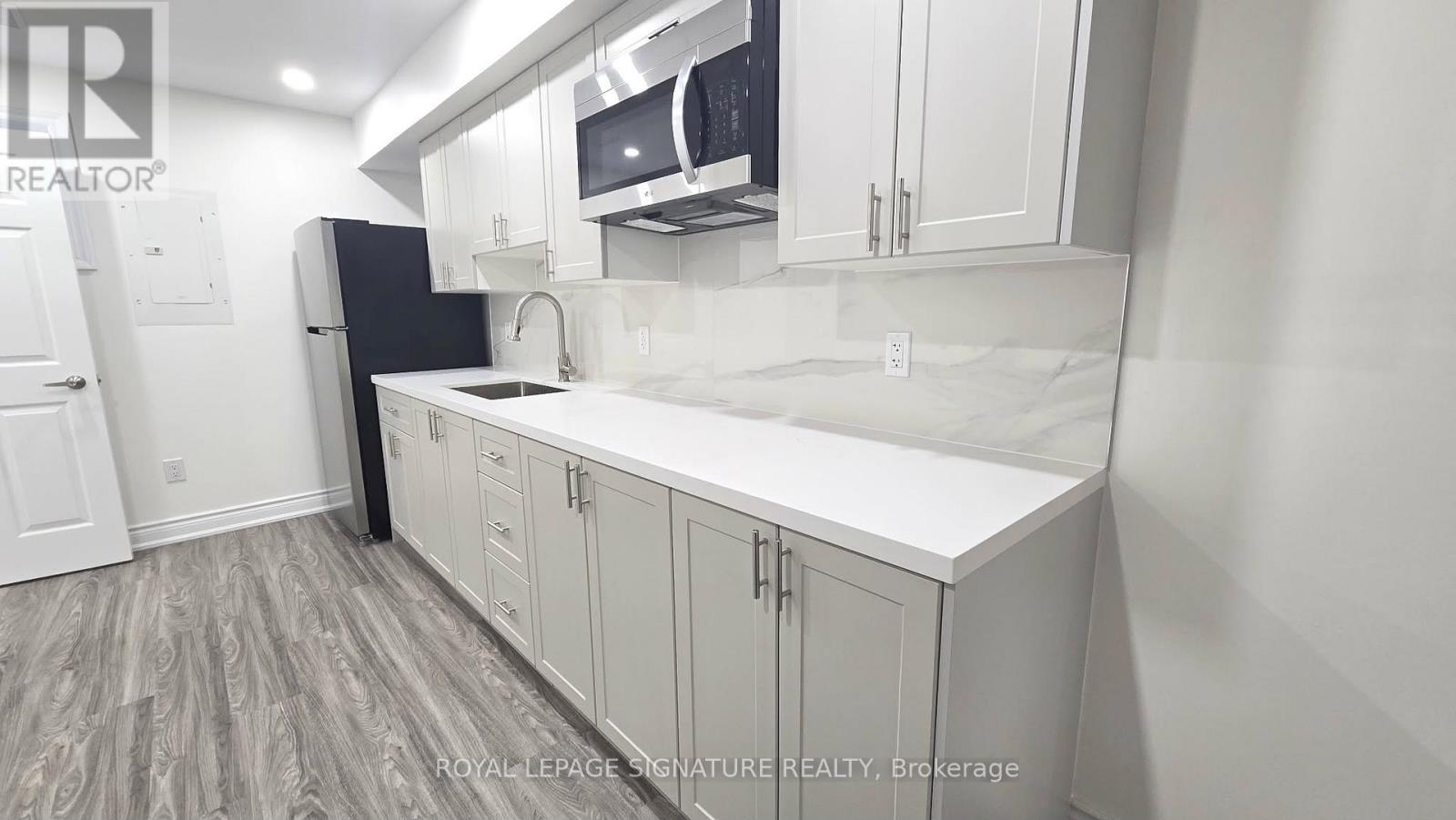 A kitchen with white cabinets and a black refrigerator.