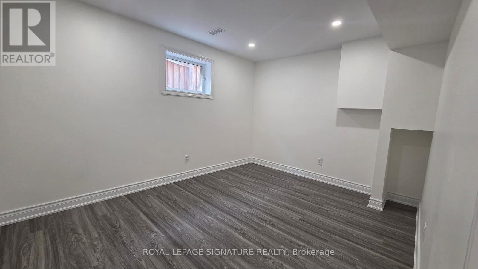 A room with a window and a wooden floor.