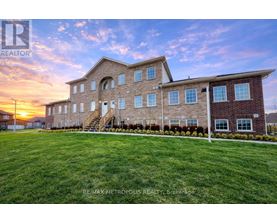 A large brick building with a grassy front yard and a sunset in the background.