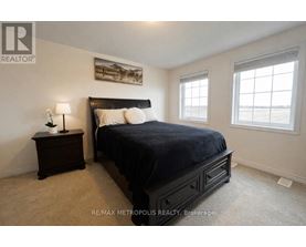 A bedroom with a large bed, a nightstand with a lamp, and a painting on the wall.
