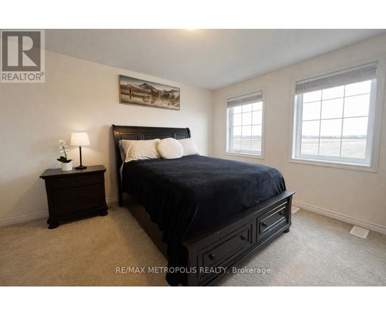 A bedroom with a large bed, a nightstand with a lamp, and a painting on the wall.