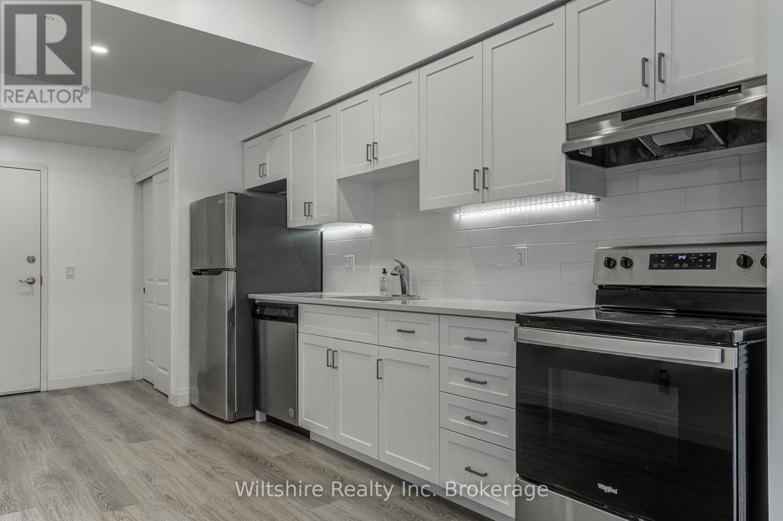 A modern kitchen with white cabinets and stainless steel appliances.