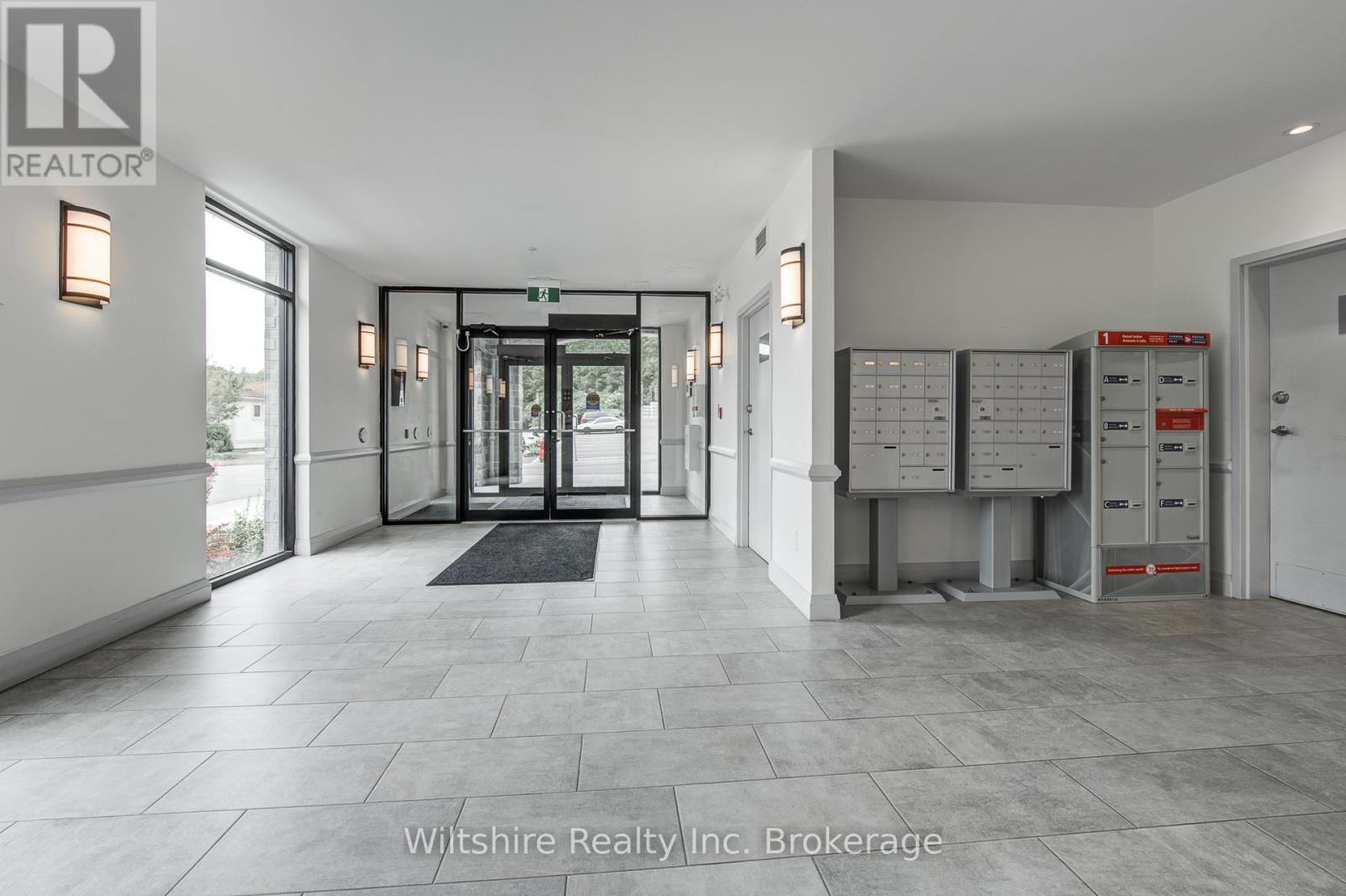 A hallway with a black mat in front of a glass door.