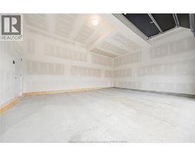 A spacious empty room with a high ceiling and skylight.