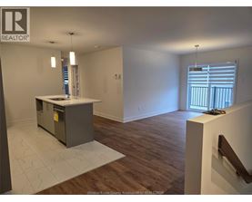 A room with a kitchen island and wooden flooring.